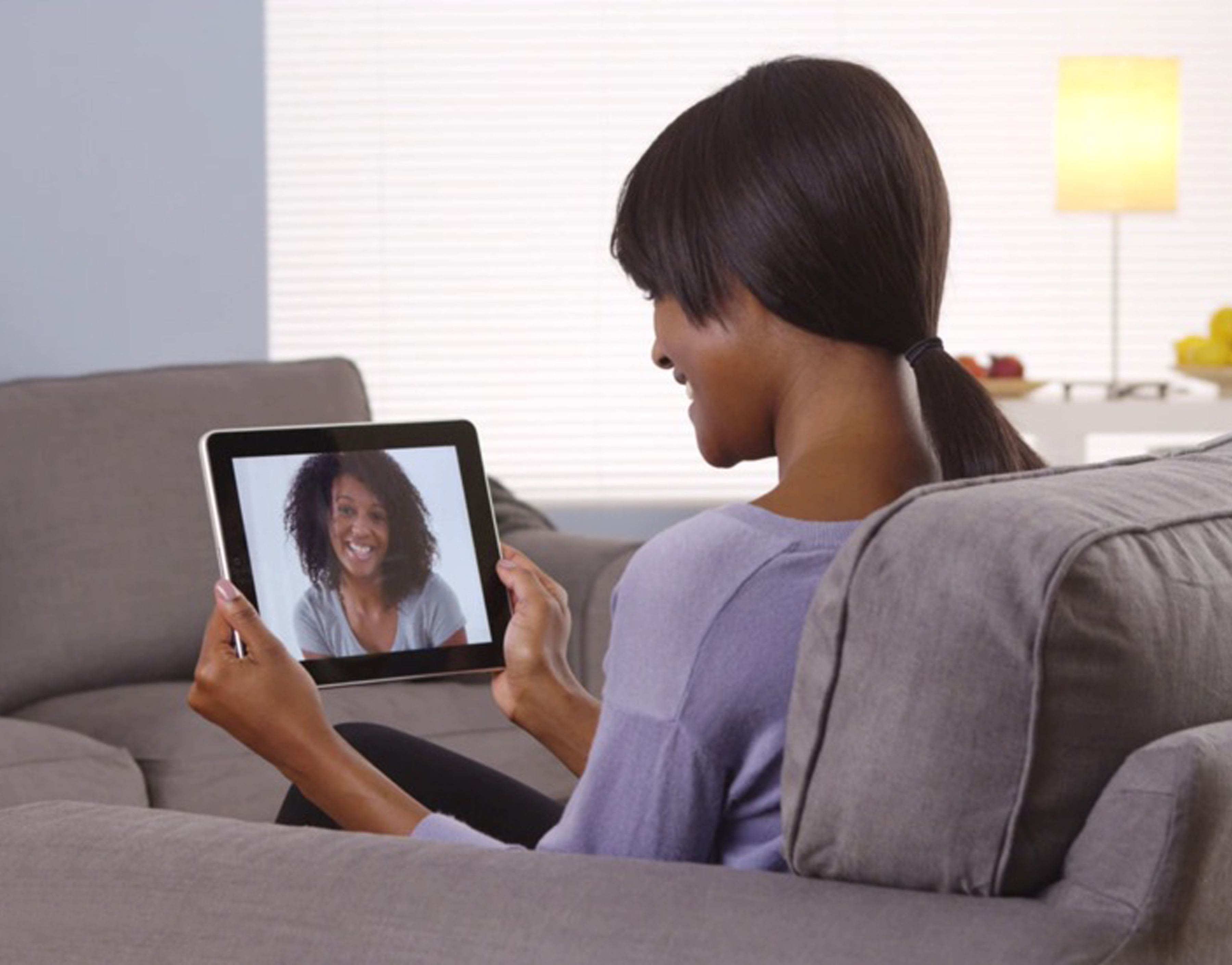 A smiling woman chats with her therapist on an ipad symbolizing personalized, compassionate mental health care for long-term wellness.